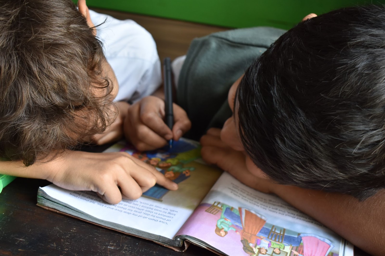 two boys writing on a picture book