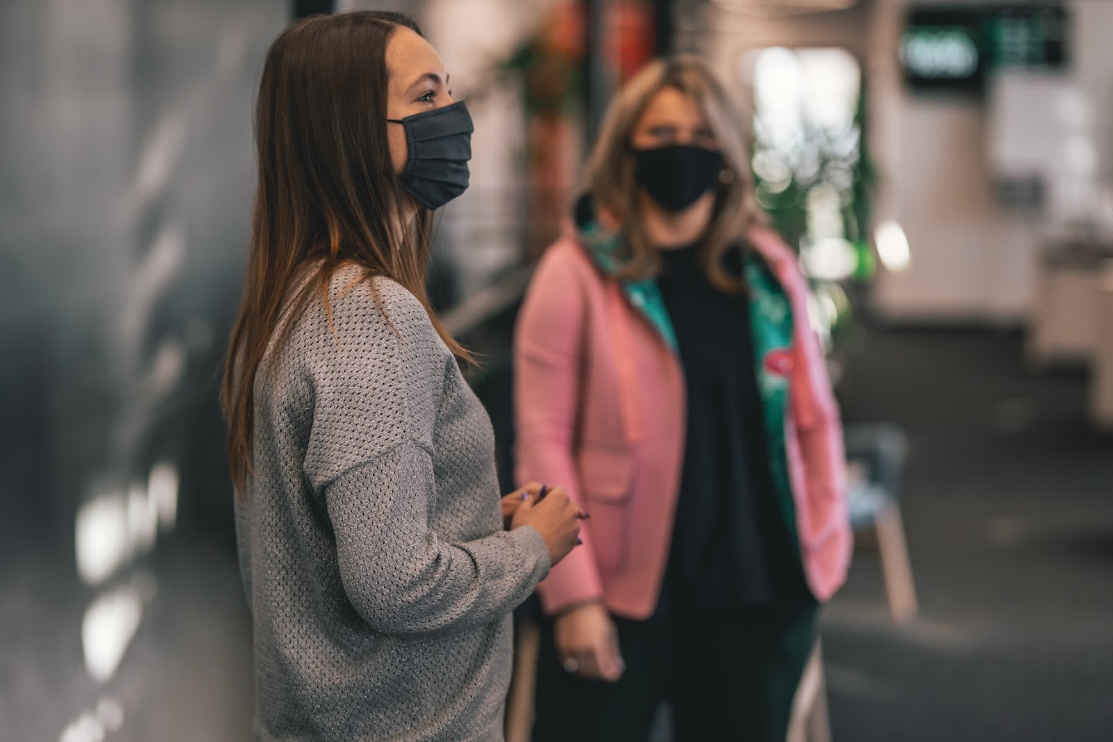 Two women chatting in an office with masks on