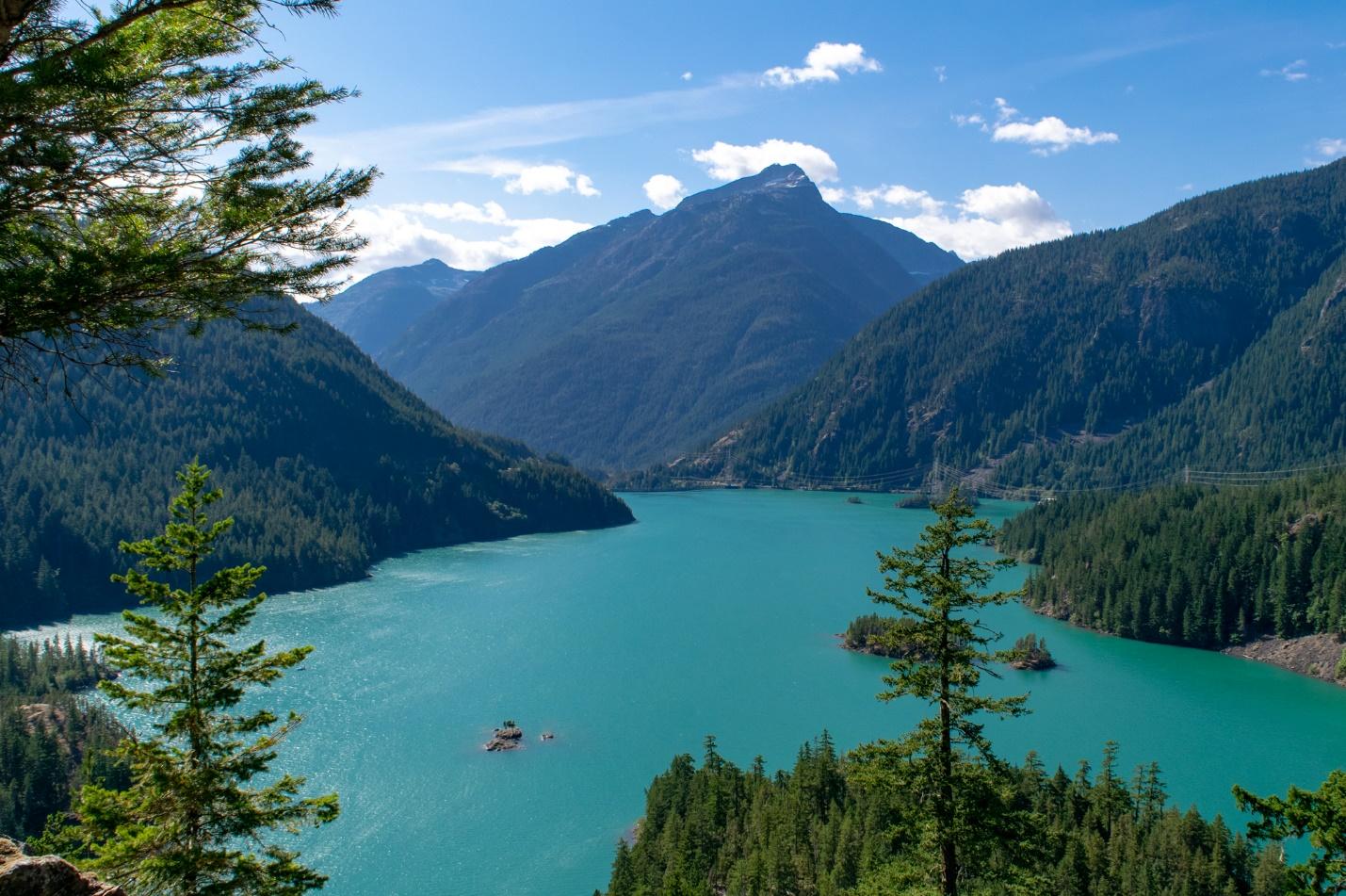 A body of water with trees and mountains in the background - Places to Visit in the Pacific Northwest