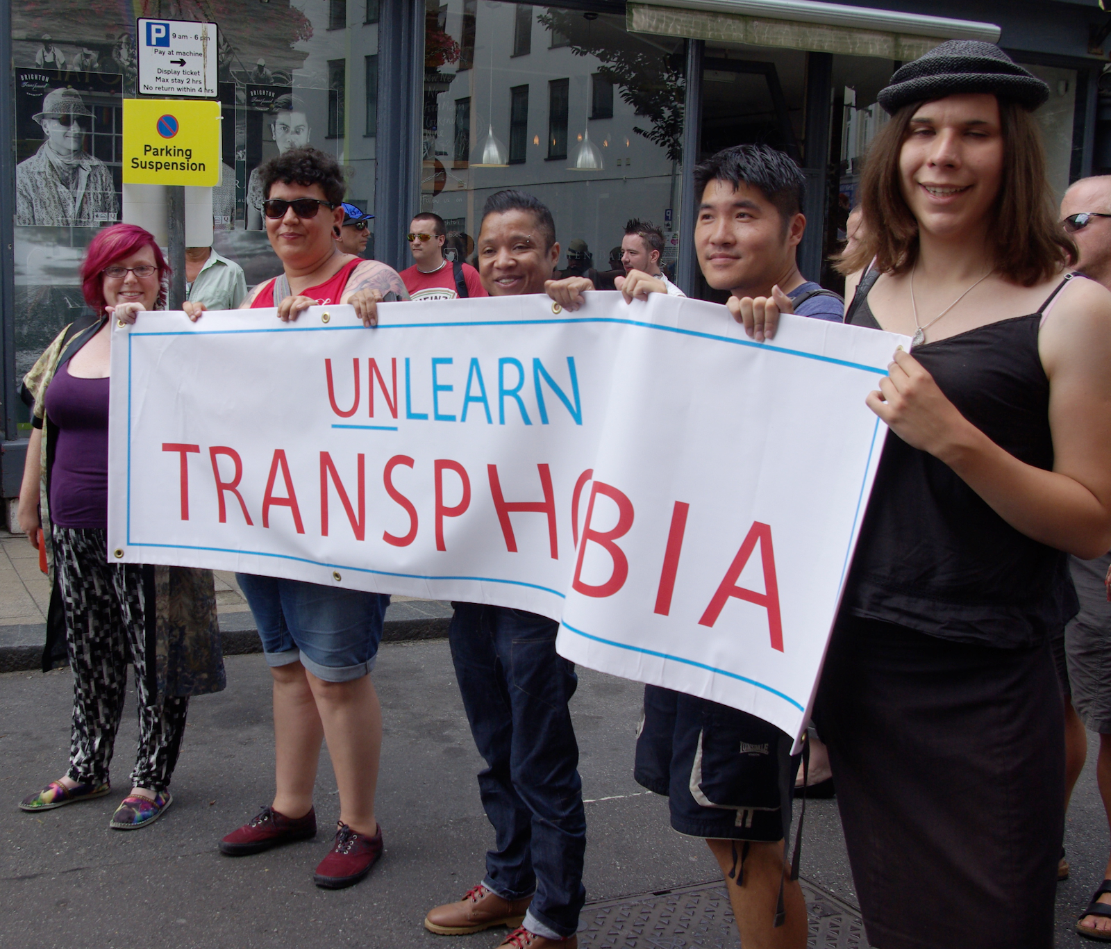 A group of people holding a banner that says "UNLEARN TRANSPHOBIA."