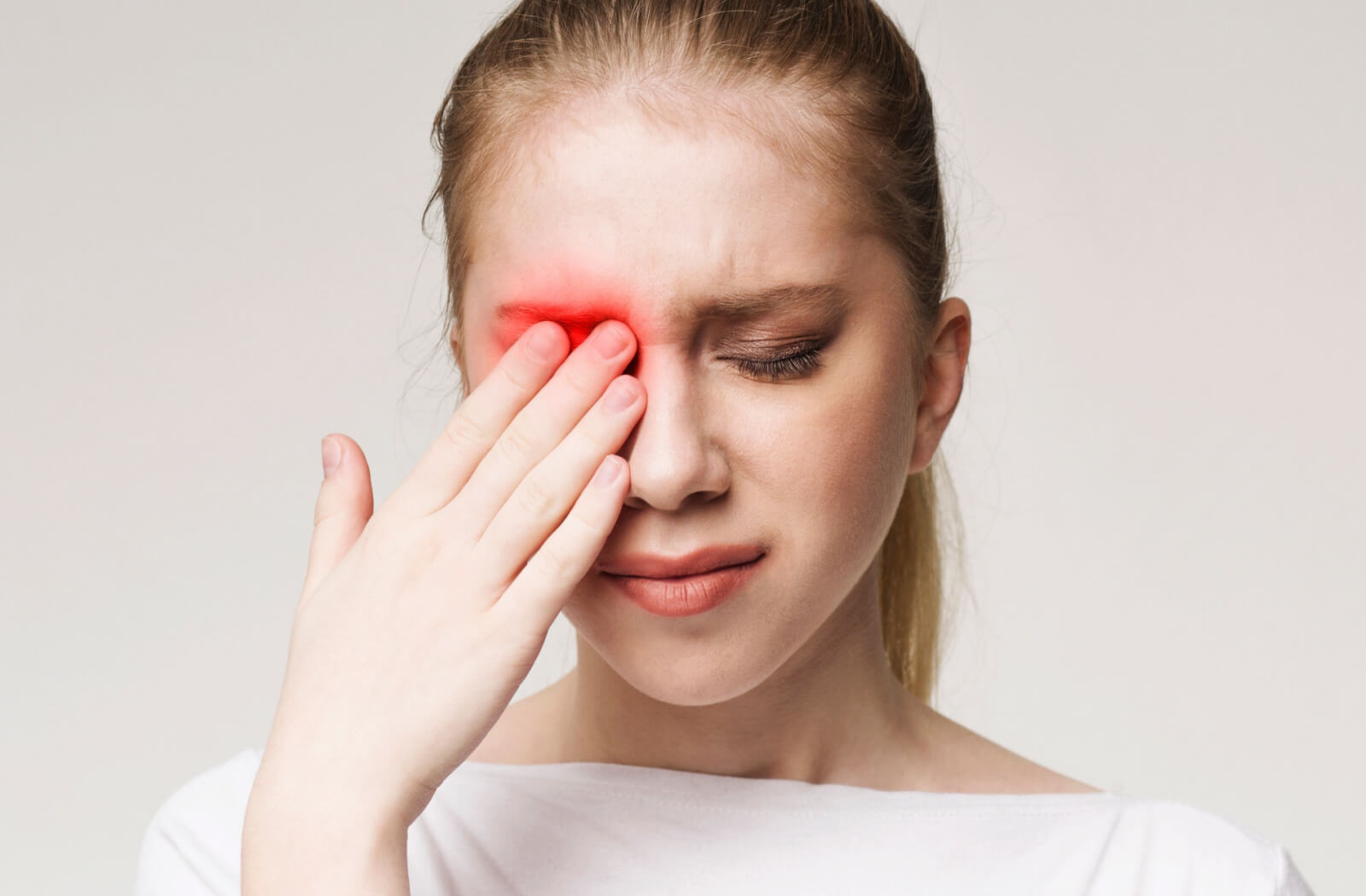 a woman wearing fake eyelashes rubs her right eye due to dryness and discomfort