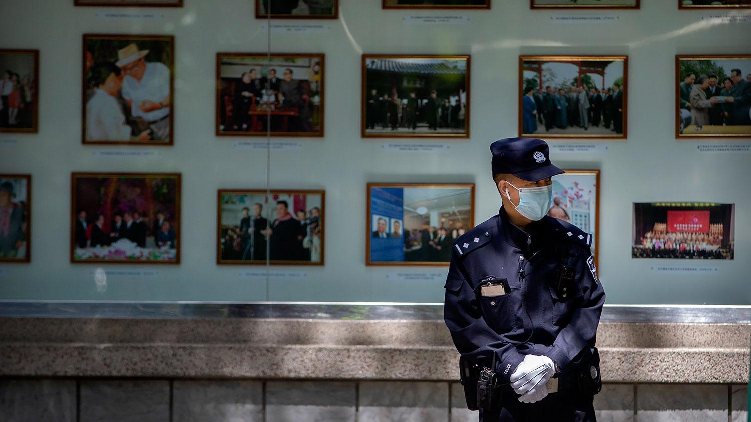 2020年4月21日,一名中国警察站在朝鲜驻北京大使馆外的朝鲜领导人照片展示前。(美联社)