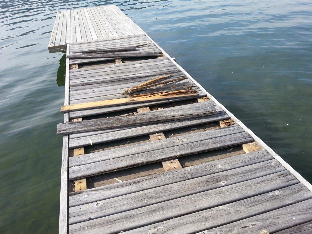 Broken wood dock above a lake.