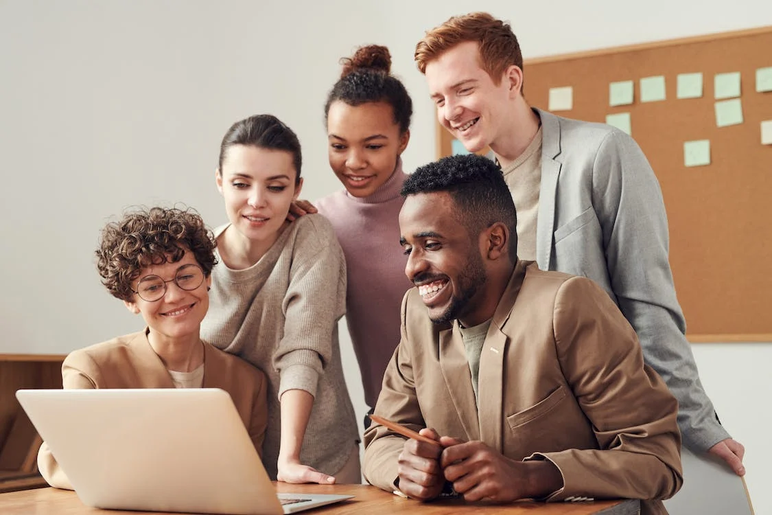 team of coworkers smiling at a computer