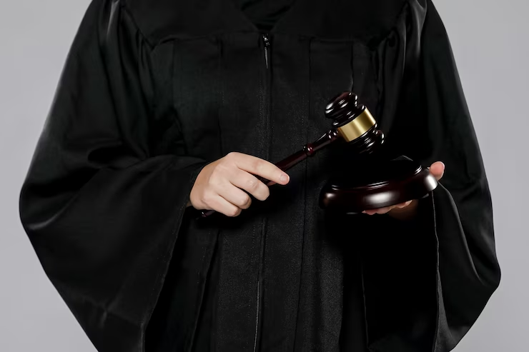 A female judge holding a gavel in a courtroom.