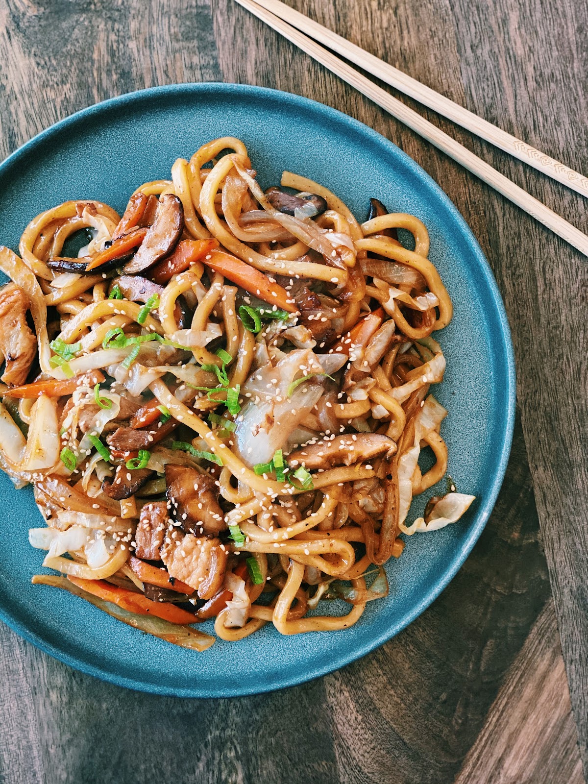 Stir-fried Yaki Udon noodles in a savory sauce with vegetables and pork, garnished with green onions, served in a bowl for a flavorful meal.