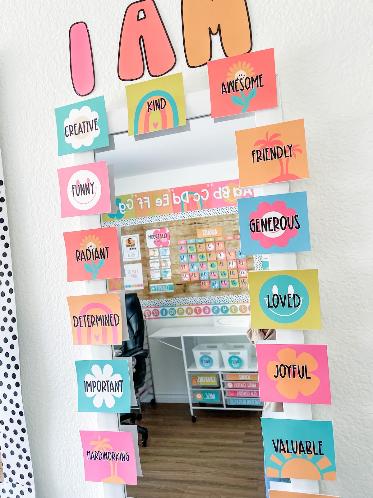 This image shows a mirror surrounded by bright-colored cards surrounding it. Above the mirror are the words "I am". There are words on each of the cards that are affirmations. These words are things like "Awesome", "Friendly", and "Determined". Each word card has an icon connected to the tropical theme.