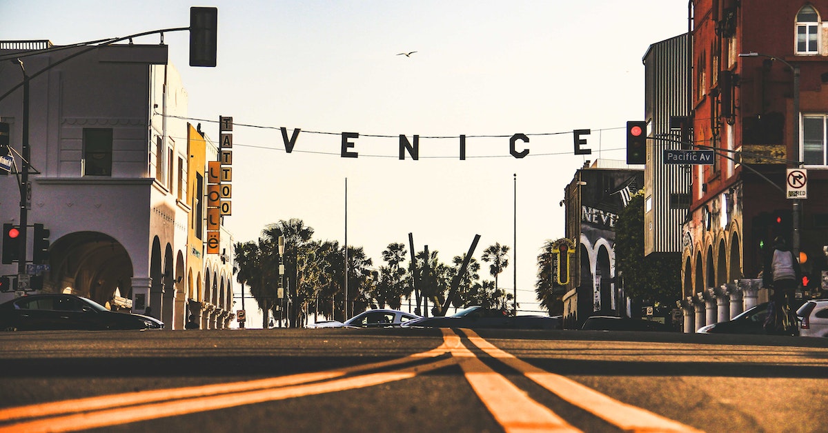 The Venice sign in Venice Beach, California with shops on either side