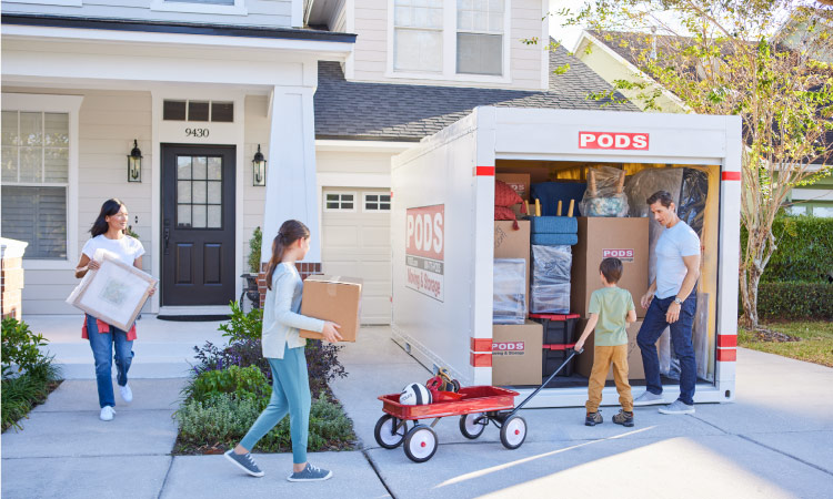 A family of four works together to carry boxes, toys, and decor from their house to the PODS moving container in their driveway. They’re preparing for their move to one of the best places to live in Georgia.