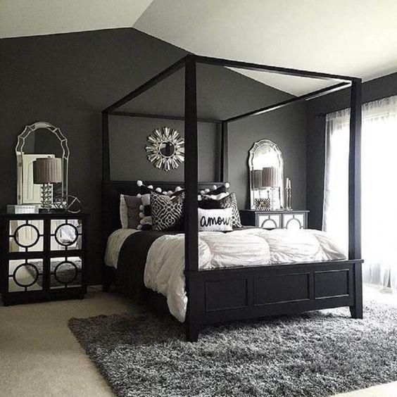 Quarto com cama de casal preta, parede pretas, penteadeiras pretas e prata e carpete cinza.