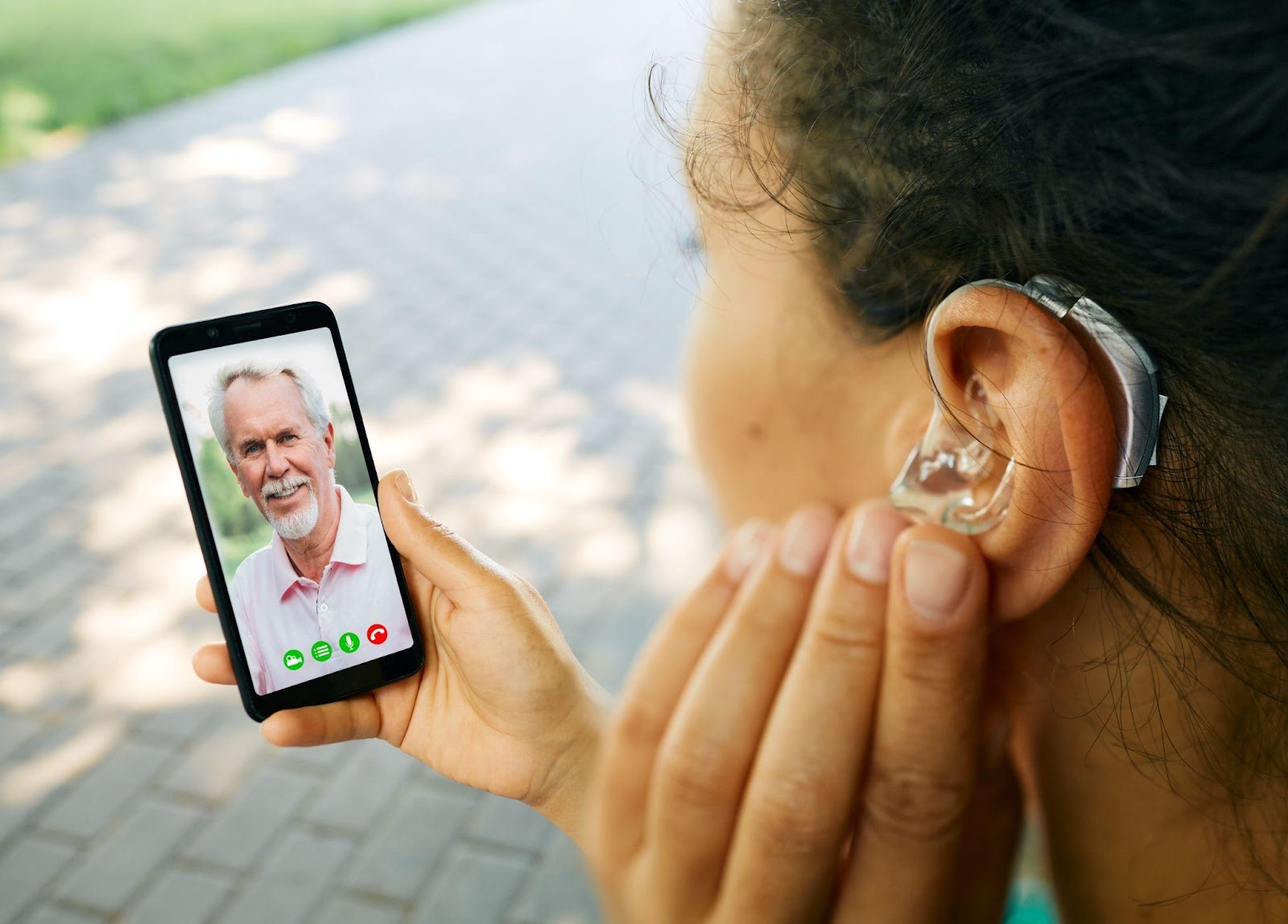 Teen calling father with bluetooth digital hearing aids.