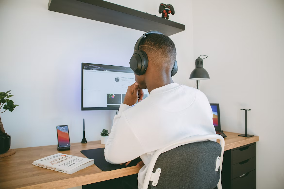 A man in white shirt sitting on chair with headphones on