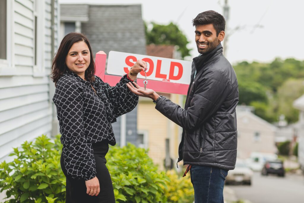 A couple next to a sold sign for a post on how to find out how much your house is worth