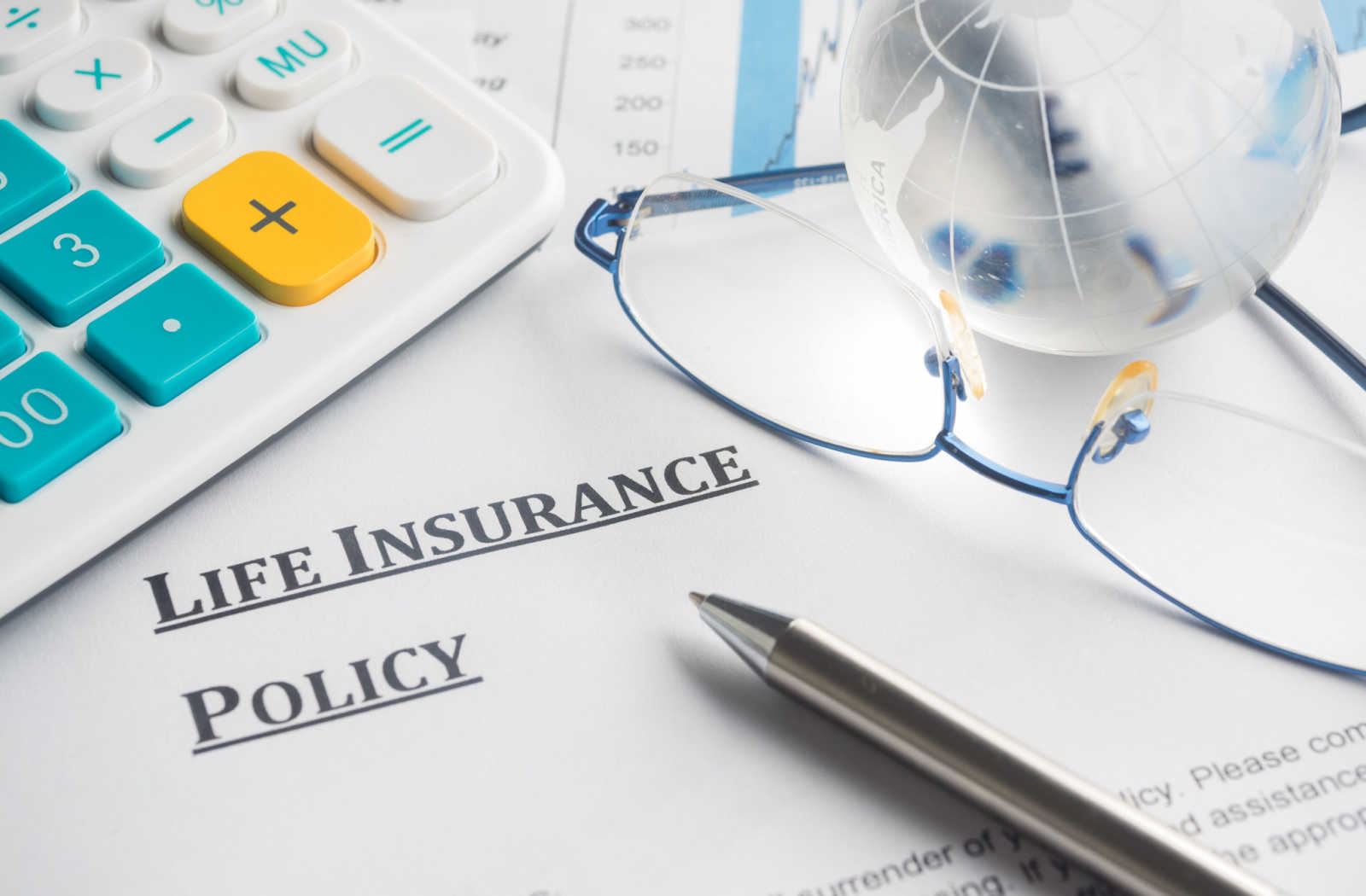 A life insurance policy laying on a desk with a pair of glasses and pen sitting on top
