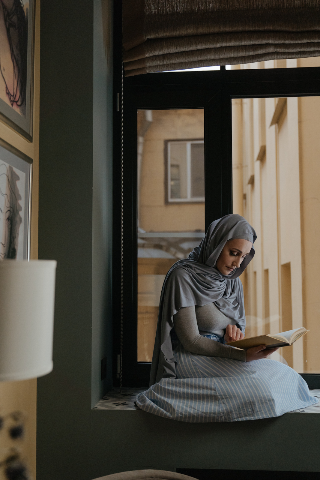 A woman reading a book by the window.