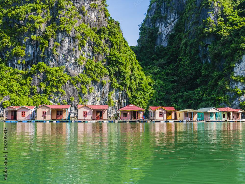 Floating fishing village reflected in emerald waters of Ha Long bay, Vietnam
