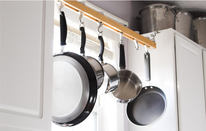 Pots and pans hanging in a kitchen window between cabinets