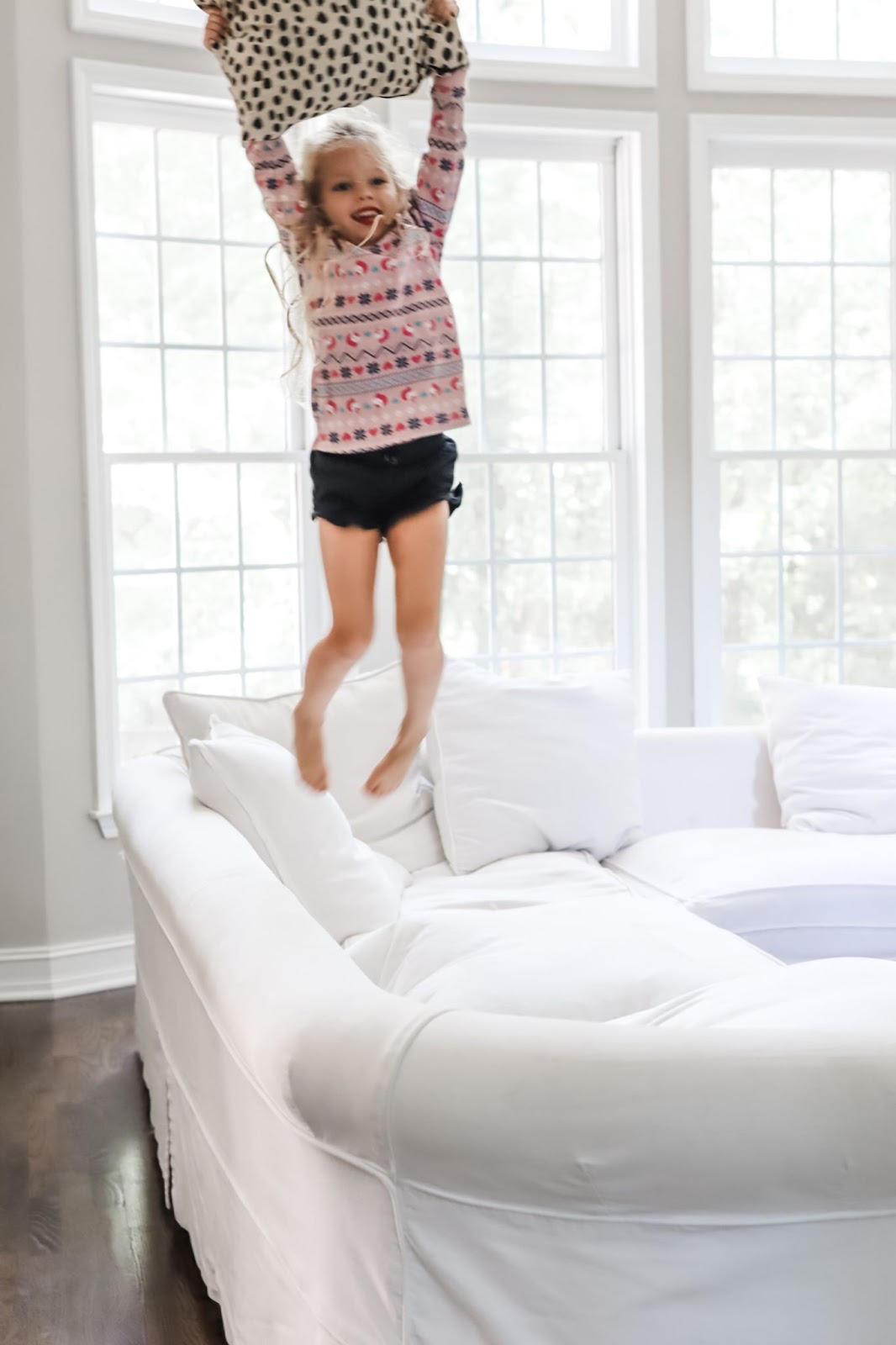Medicine Cabinet Ideas by popular Atlanta lifestyle blog, City Peach: image of a little girl jumping on a white sectional couch.