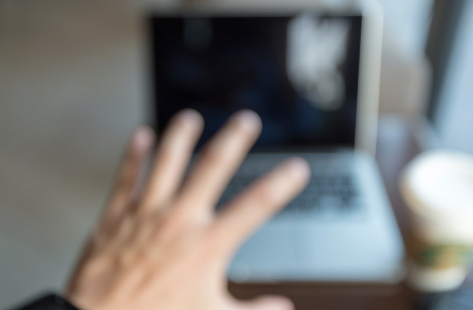  A blurred image of a man reaching out towards his computer