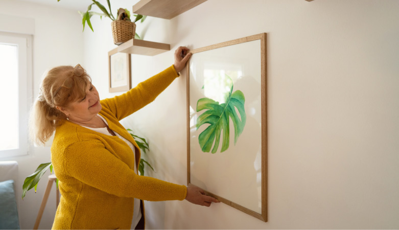 A woman hanging art on the wall of her home office