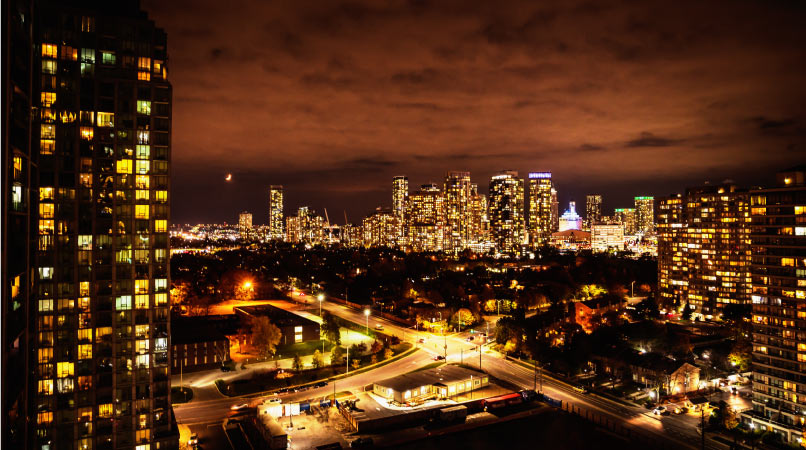 Skyscrapers are lit up against a dark and cloudy sky in Mississauga, Ontario, Canada. 