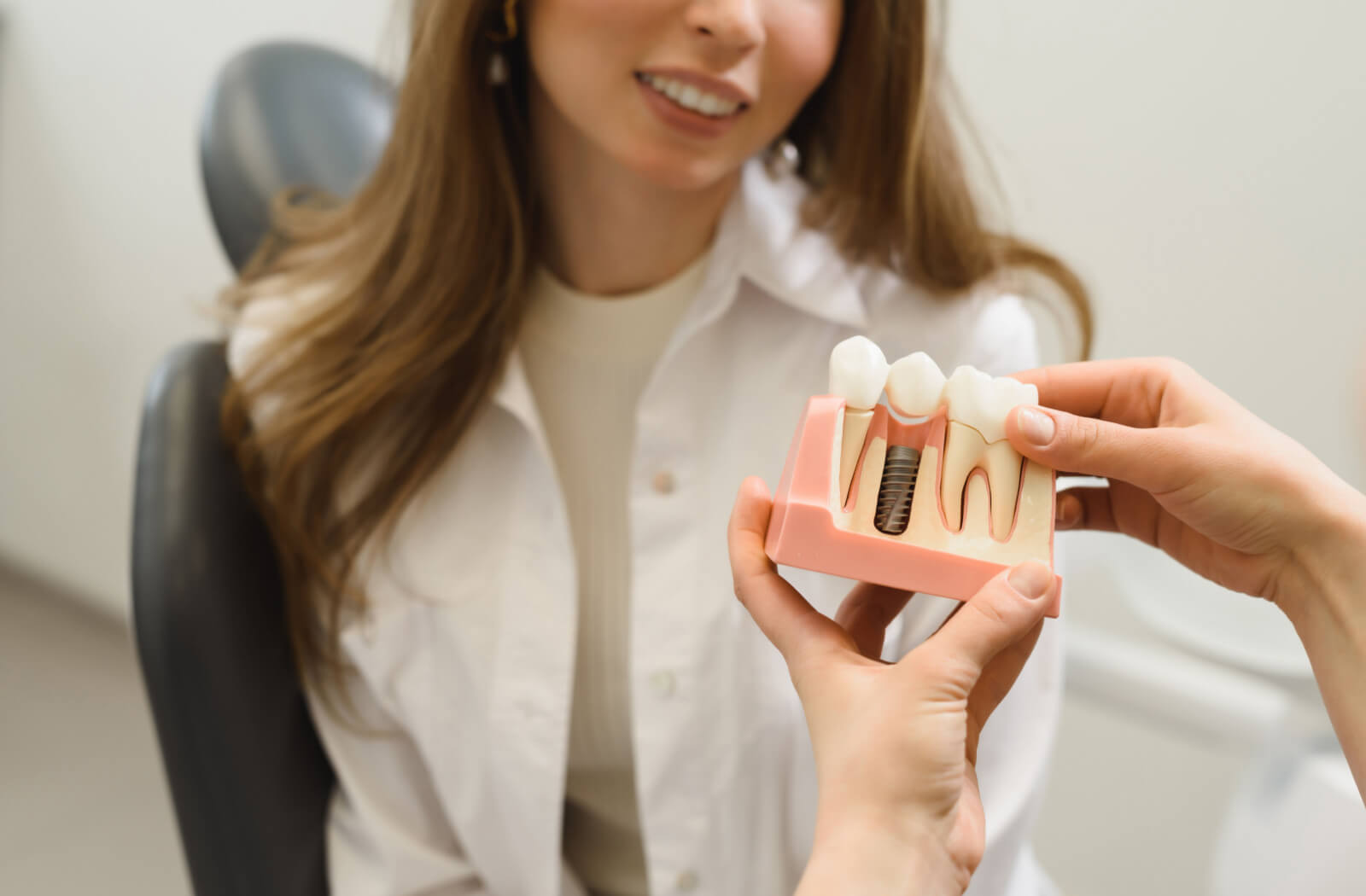 The dentist is showing a model of a dental implant to her patient.