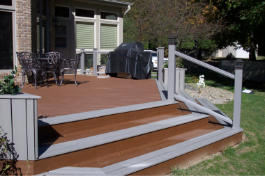composite deck with glass railings chairs and BBQ grill custom built lansing michigan