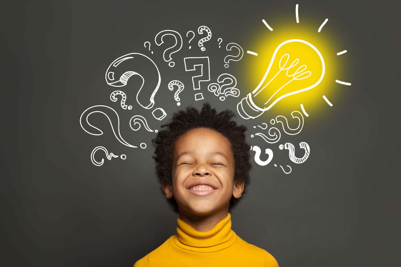 A child with question marks and a light bulb overhead, showing his computational thinking