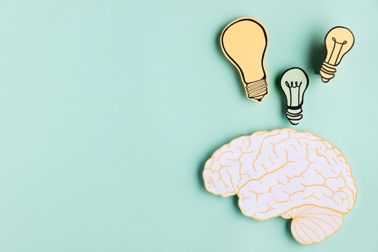 Uma montagem mostrando uma representação do cérebro tendo três lâmpadas desenhadas acima.