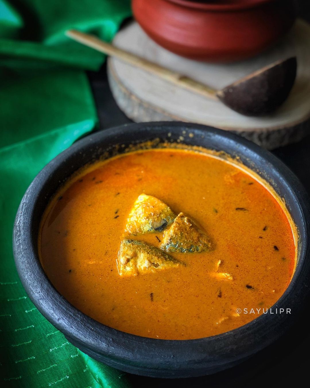 Goan dish orange fish curry with pieces of fish in it