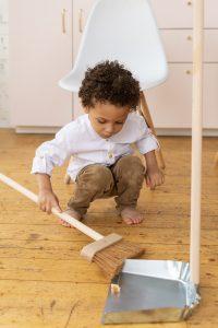 a boy helping in sweeping the floor