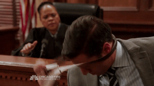 ADA Barba from Law & Order SVU in the courtroom removing a belt from around his neck.
