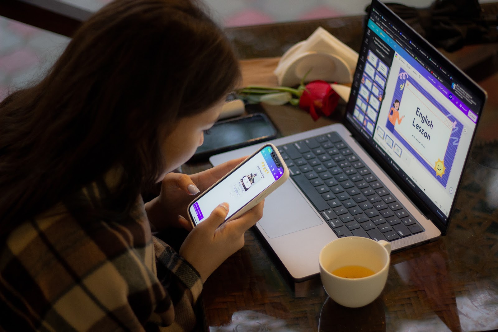 A woman preparing for her English lesson through her laptop and phone.