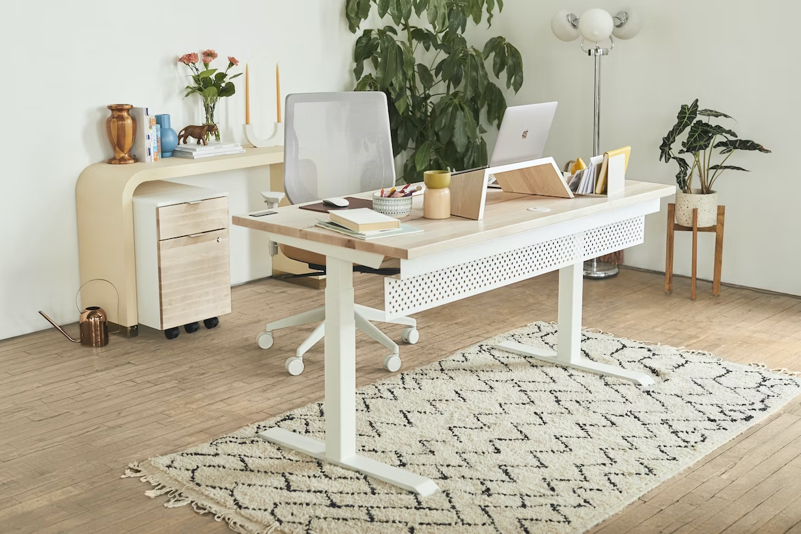 A workspace with a standing desk, an ergonomic chair, and a laptop on top of the desk