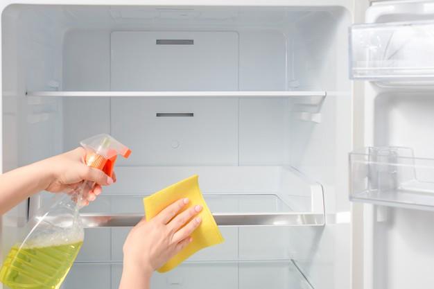 WeServe deep cleaning an empty fridge with cloth and detergent as part of home maintenance services