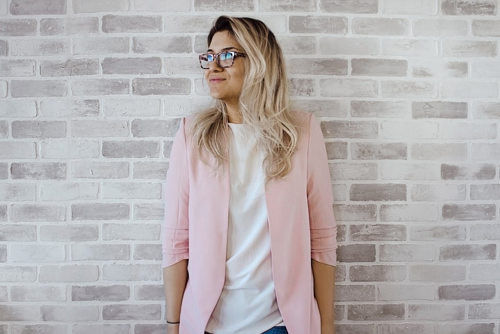 woman with pink jacket leaning on wall 