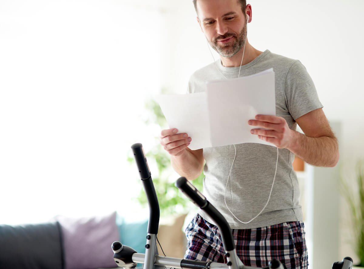 Man reading some documents while exercising at home