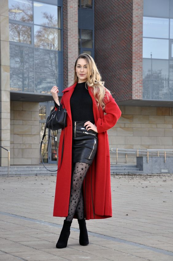 a laldy layering her black miniskirt and top with a long red coat