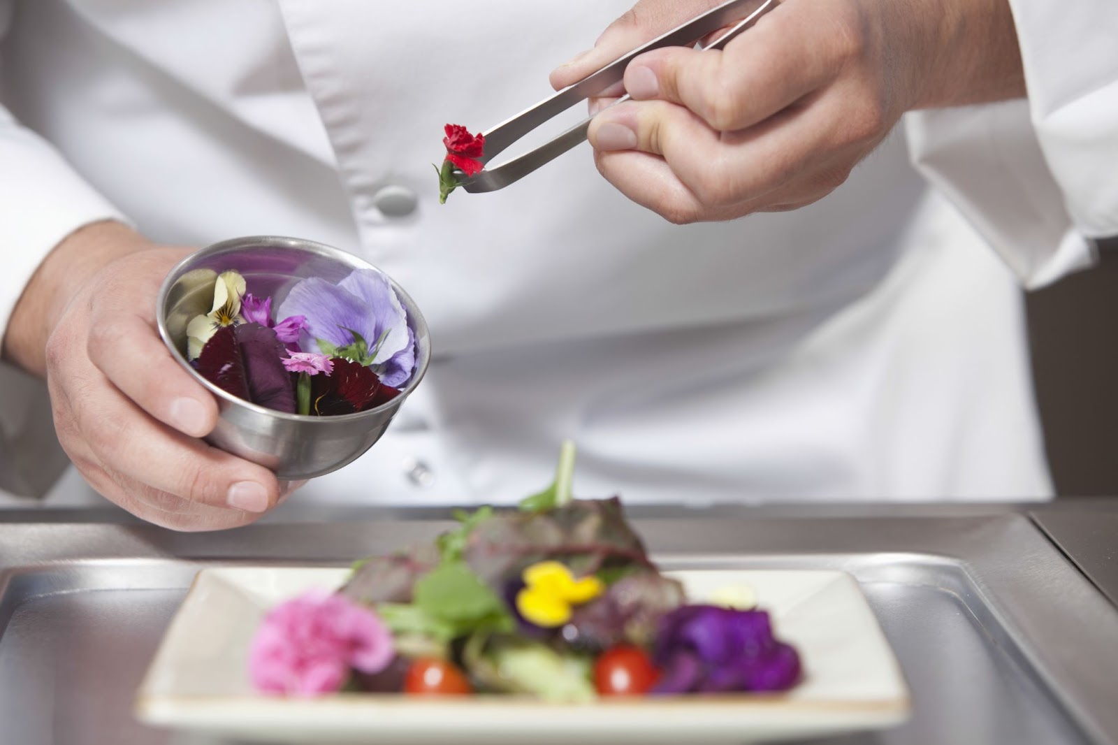 A chef adding Edible flowers to their food prep.