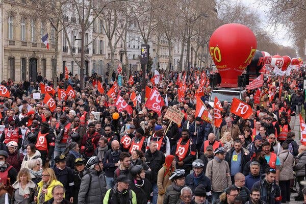 A dense crowd of protesters in the street, with many holding red flags.