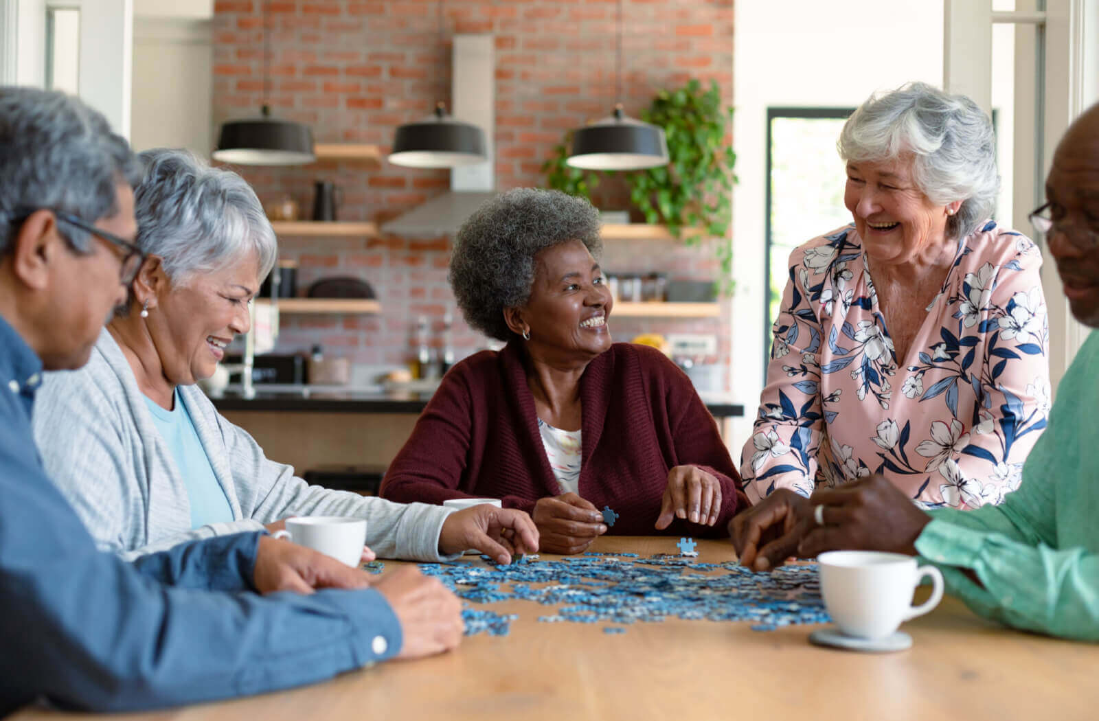 A group of seniors sit around a table doing a puzzle
