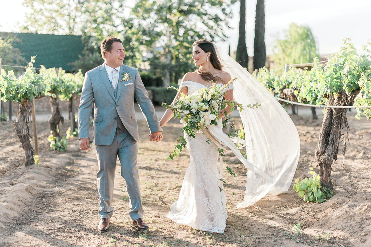 couple holding hands in vineyard