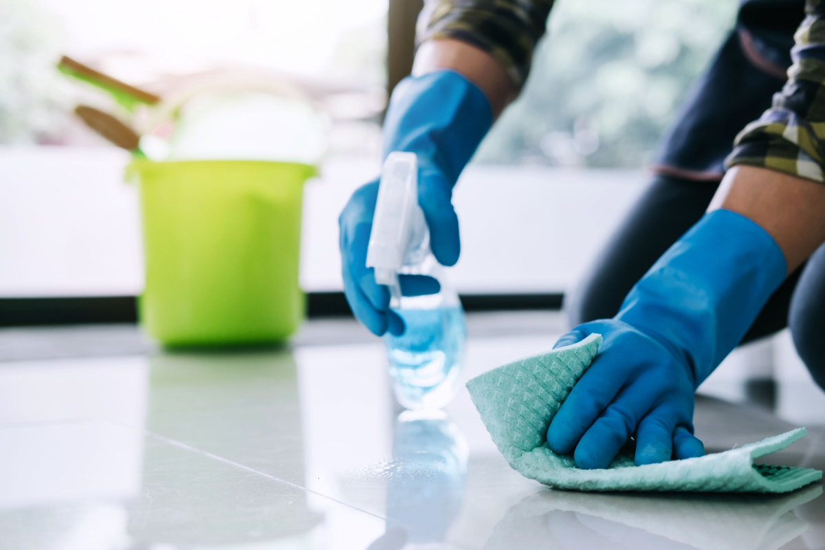 A person wearing gloves and cleaning the floor.