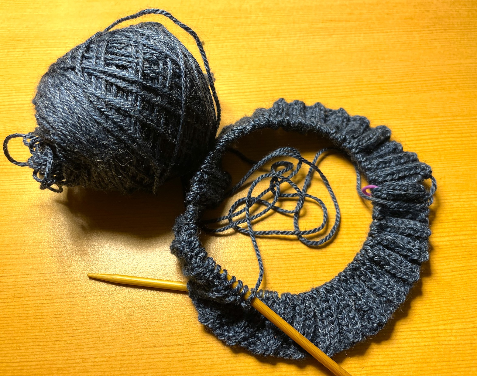 A ball of blue yarn and the beginning of a knitting project on circular knitting needles