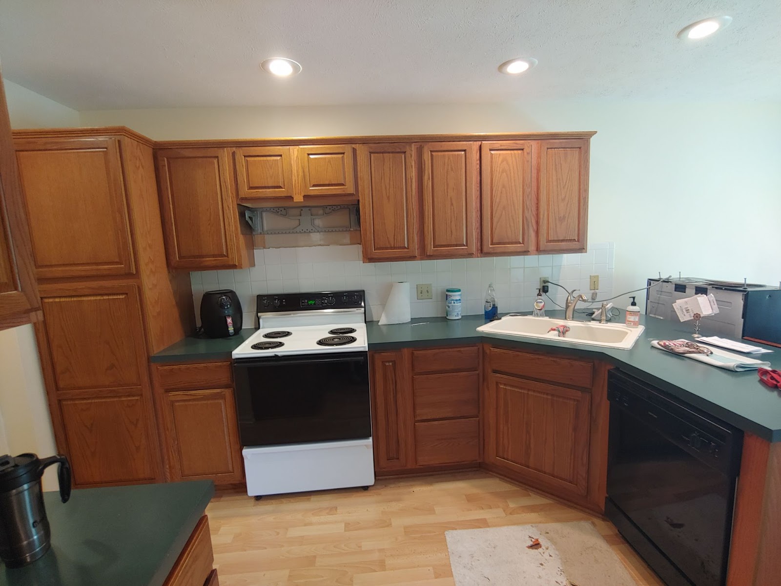 Stained kitchen cabinets with green countertops, a stove, and a dishwasher