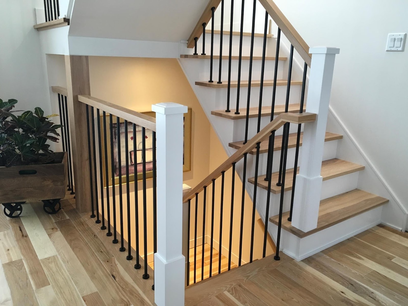Wooden staircase with black metal handrail.