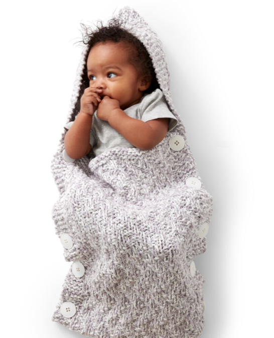 baby lying in knit bunting bag on white background