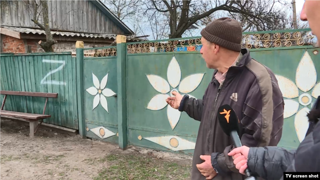 Мешканець села Іванівка показує напис, який зробили на його загорожі російські солдати