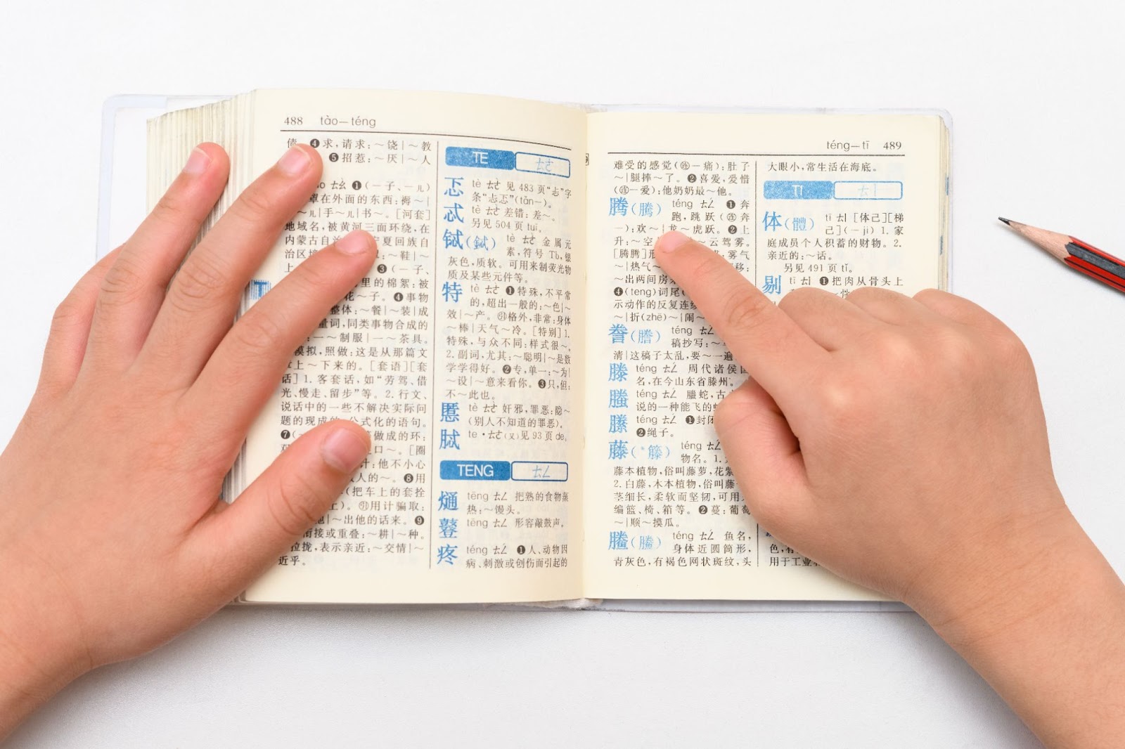 A kid is memorizing many Chinese vocabularies from a thick dictionary.