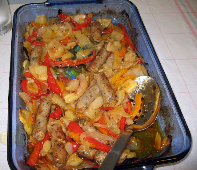Baked sausage and peppers dish featuring red and orange peppers.